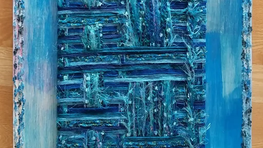 The piece features a painted abstract background in fluid shades of light and dark blue acrylic, resembling water. Overlaid in the center is a heavily textured, woven square made of interlaced blue, teal, and green threads forming a grid pattern. Two vertical bands of similar frayed threads run from the top to the bottom of the canvas, passing beneath the central square. The artwork is framed by a thin, fuzzy border of textured blue thread.